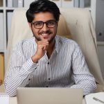 Portrait of Indian handsome business executive sitting at table