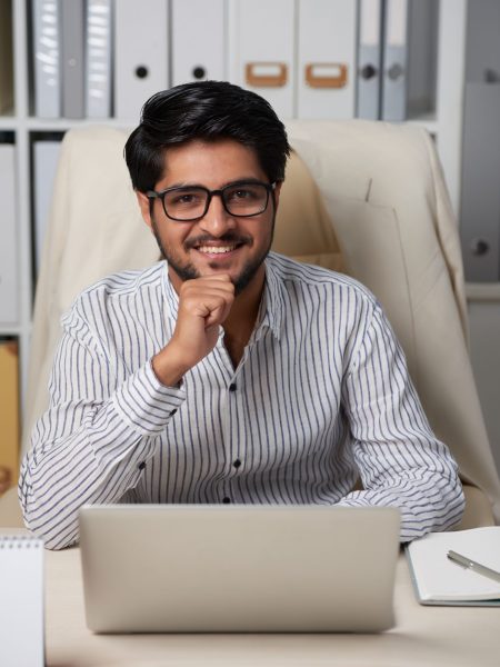 Portrait of Indian handsome business executive sitting at table